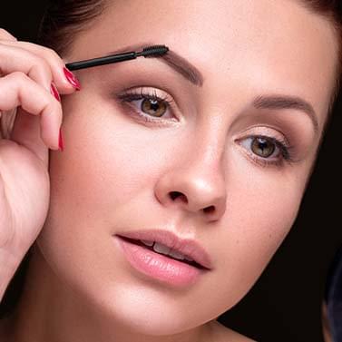 Blonde vrouw die de wenkbrauwgel gebruikt