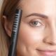Model glimlachend, met de Nanobrow Shape Mascara dicht bij zich ear