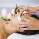 Een persoon die een ontspannende gezichtsmassage krijgt in een serene spa-omgeving met kaarsen op de achtergrond.