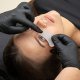 Een vrouw die een ooglidbehandeling ondergaat terwijl ze hydrogel-oogpatches draagt, met een serene en gefocuste uitdrukking.